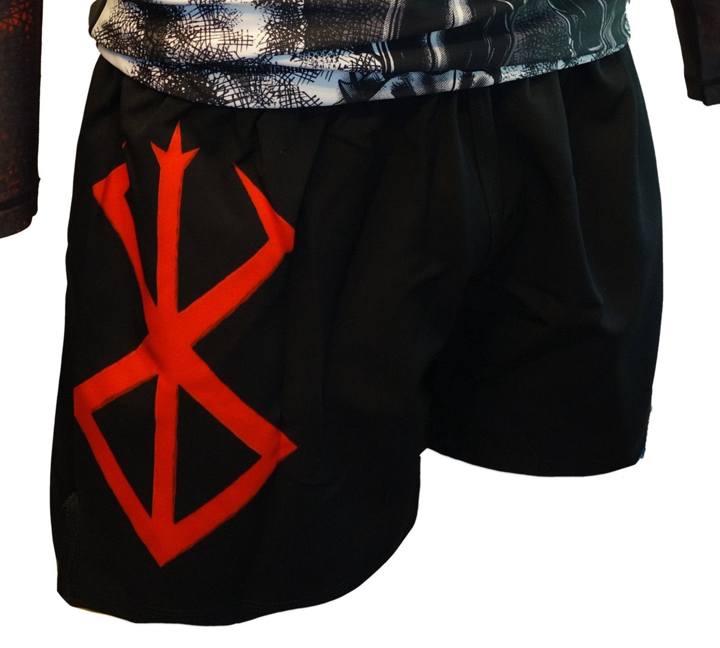 The Retro Grappler Berserk Lightweight BJJ Shorts are black with a bold red rune design on the left leg. Shown worn by a standing model, they offer added comfort with no Velcro and pair well with an athletic black-and-white shirt.