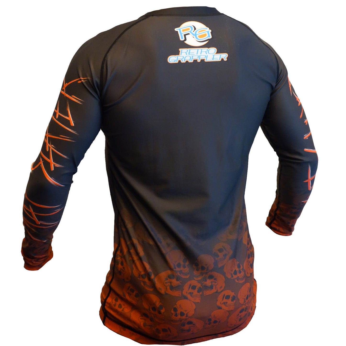 The Mat Slayer BJJ Rash Guard by Retro Grappler features long sleeves, a black and orange design with skull patterns on the lower half, abstract orange lines on the sleeves, and the brands logo on the back—a bold choice for jiu jitsu athletes.